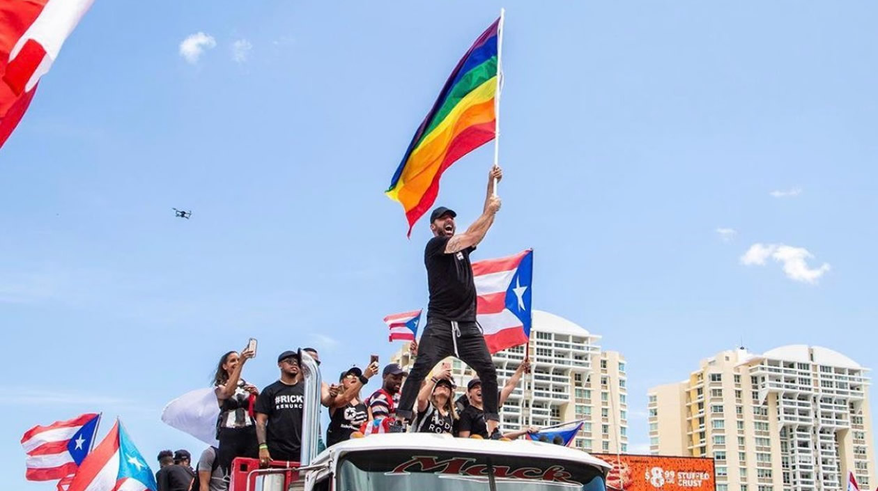 Ricky Martín ondeando una bandera de dos caras (LGBTI y Puerto Rico).