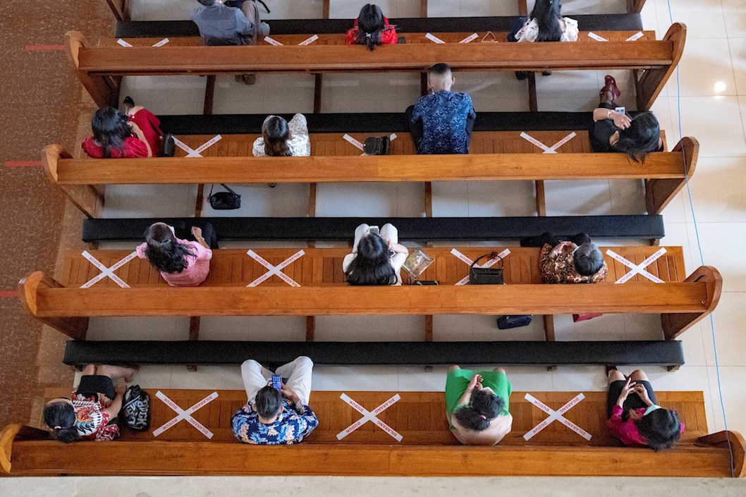 Varios fieles guardan la distancia social mientras asisten a una misa de Nochebuena en una catedral de Denpasar, Bali (Indonesia).