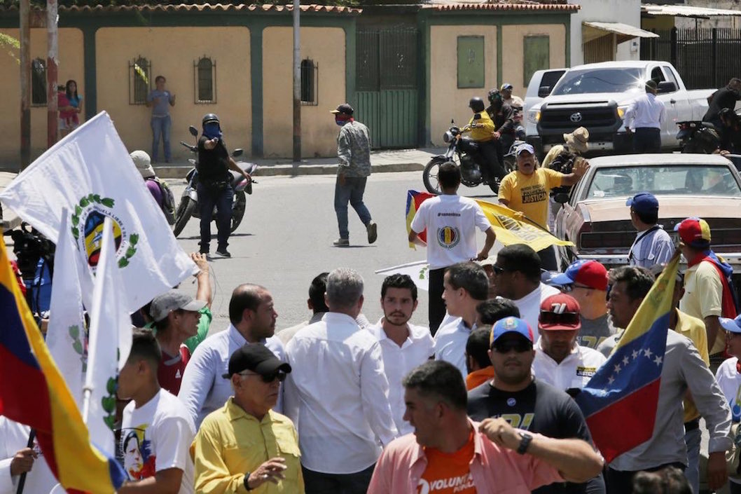 Un hombre armado apuntando al grupo donde se encontraba Juan Guaidó.