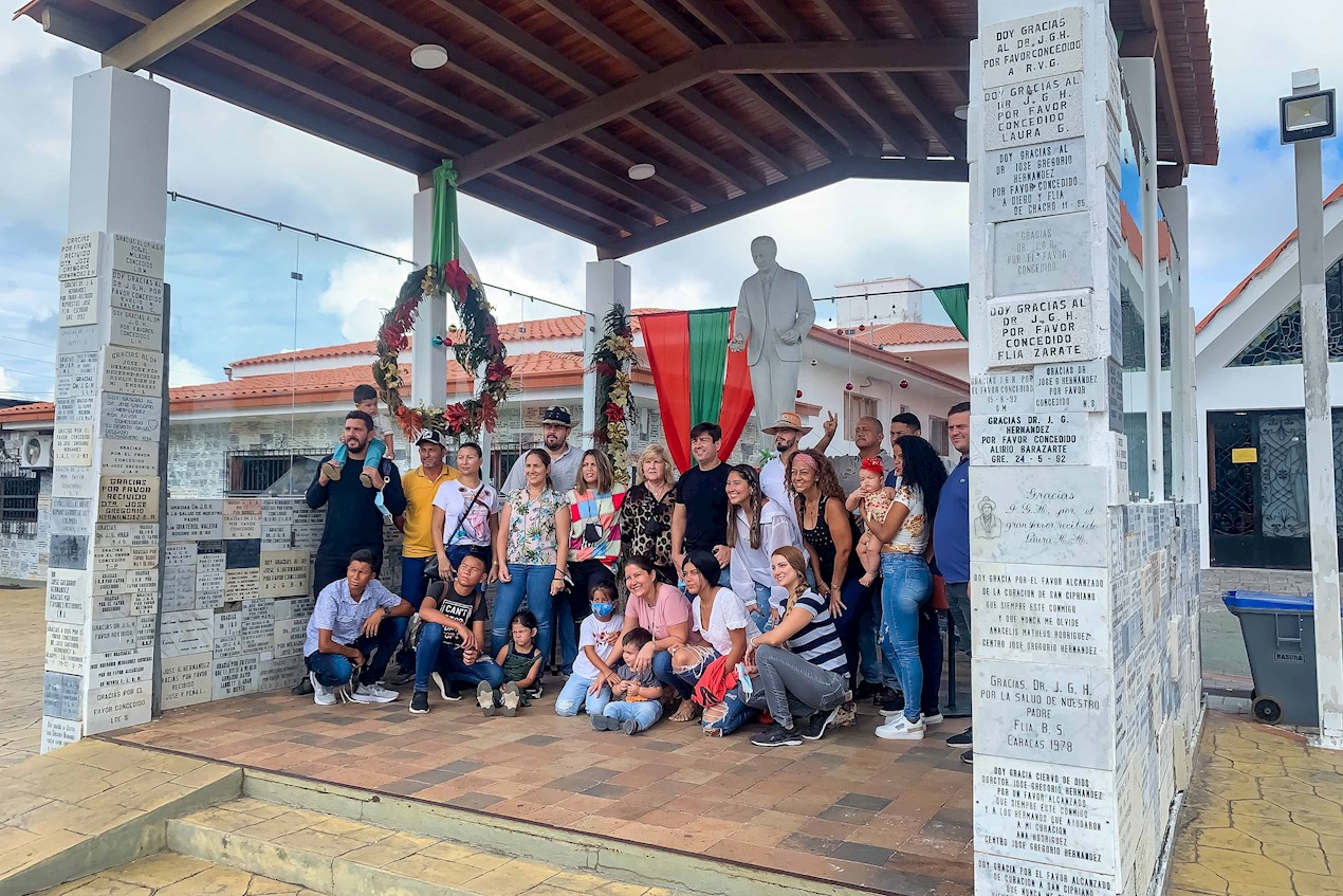 Un grupo de personas posar junto a una estatua de José Gregorio Hernández, en Isnotú (Venezuela). 