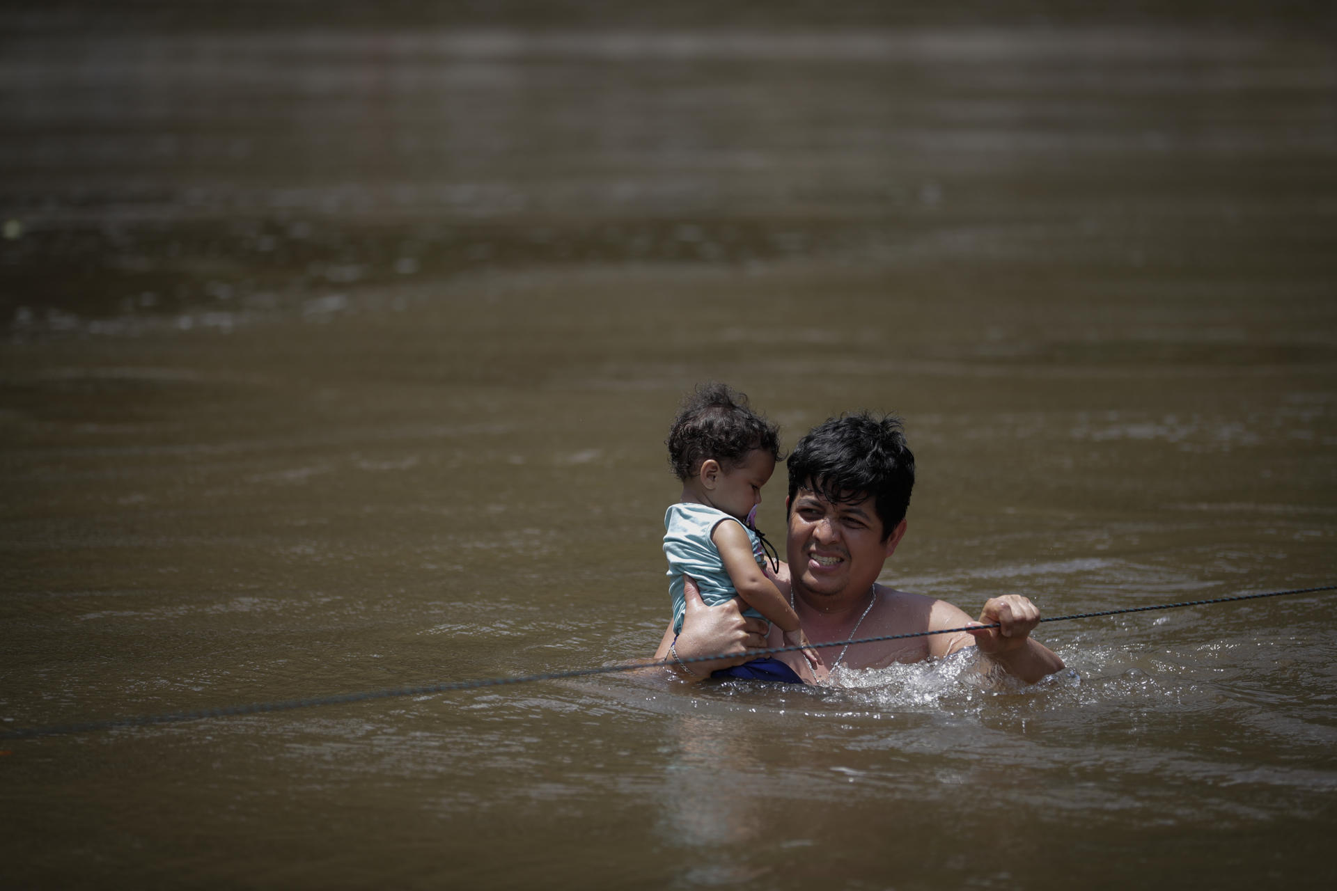 Migrantes cruzando un río con un niño en la selva del Darién. 