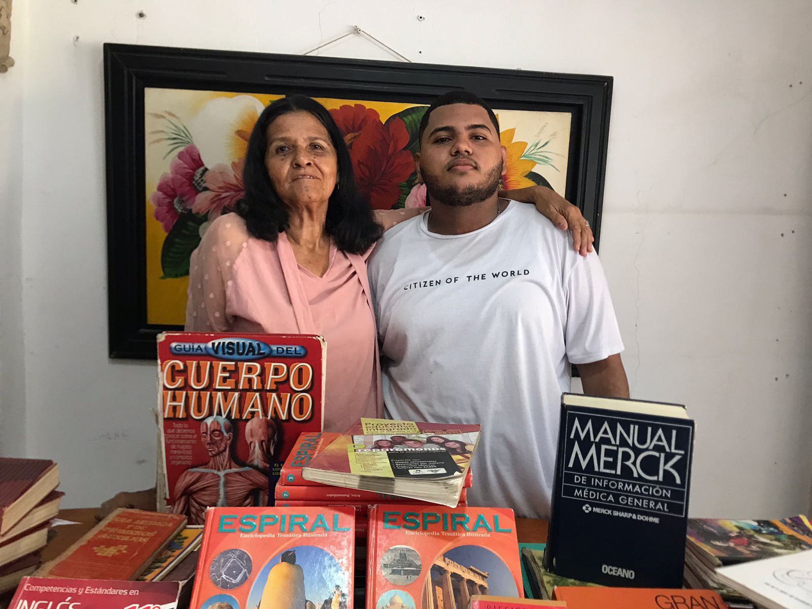 Abuela y nieto rodeados de los libros que hacen parte de la biblioteca de Fabiola