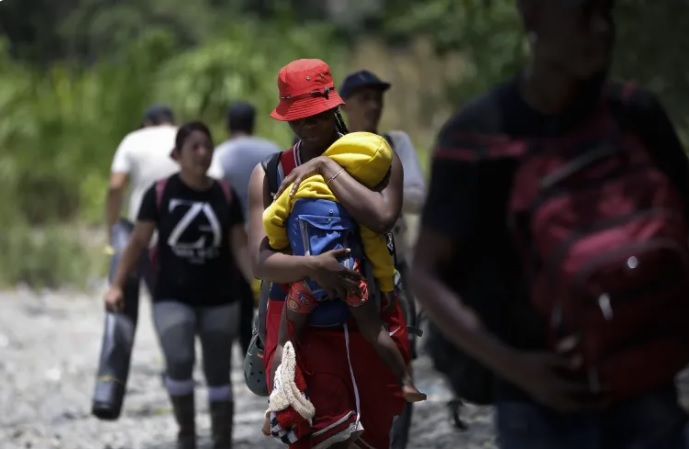  Una migrante haitiana carga a su hijo en la selva mientras esperan para ser trasladados en canoa por el Darien