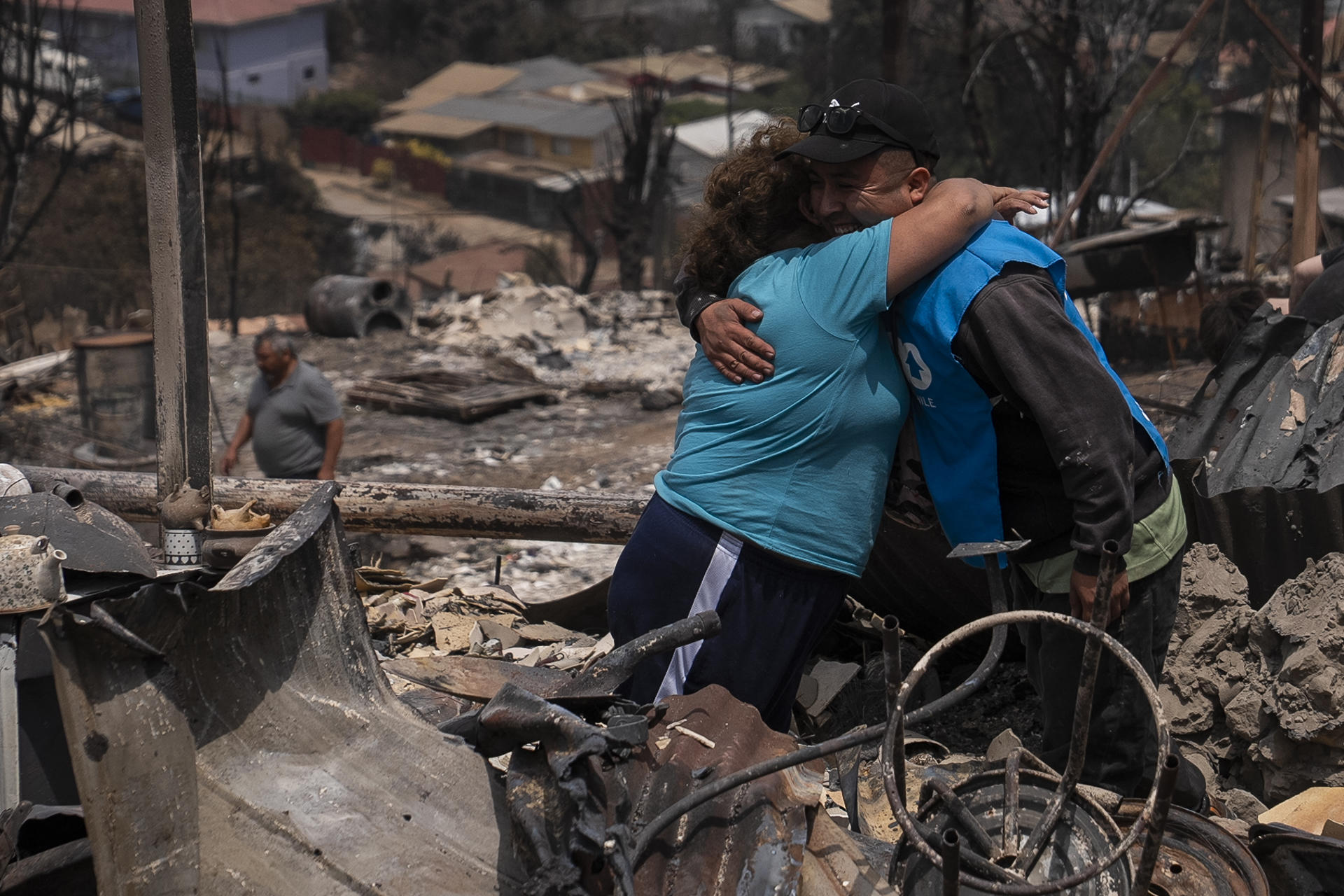 Personas se abrazan en una casa en el sector de Achupallas afectada por incendios forestales de Viña del Mar, 