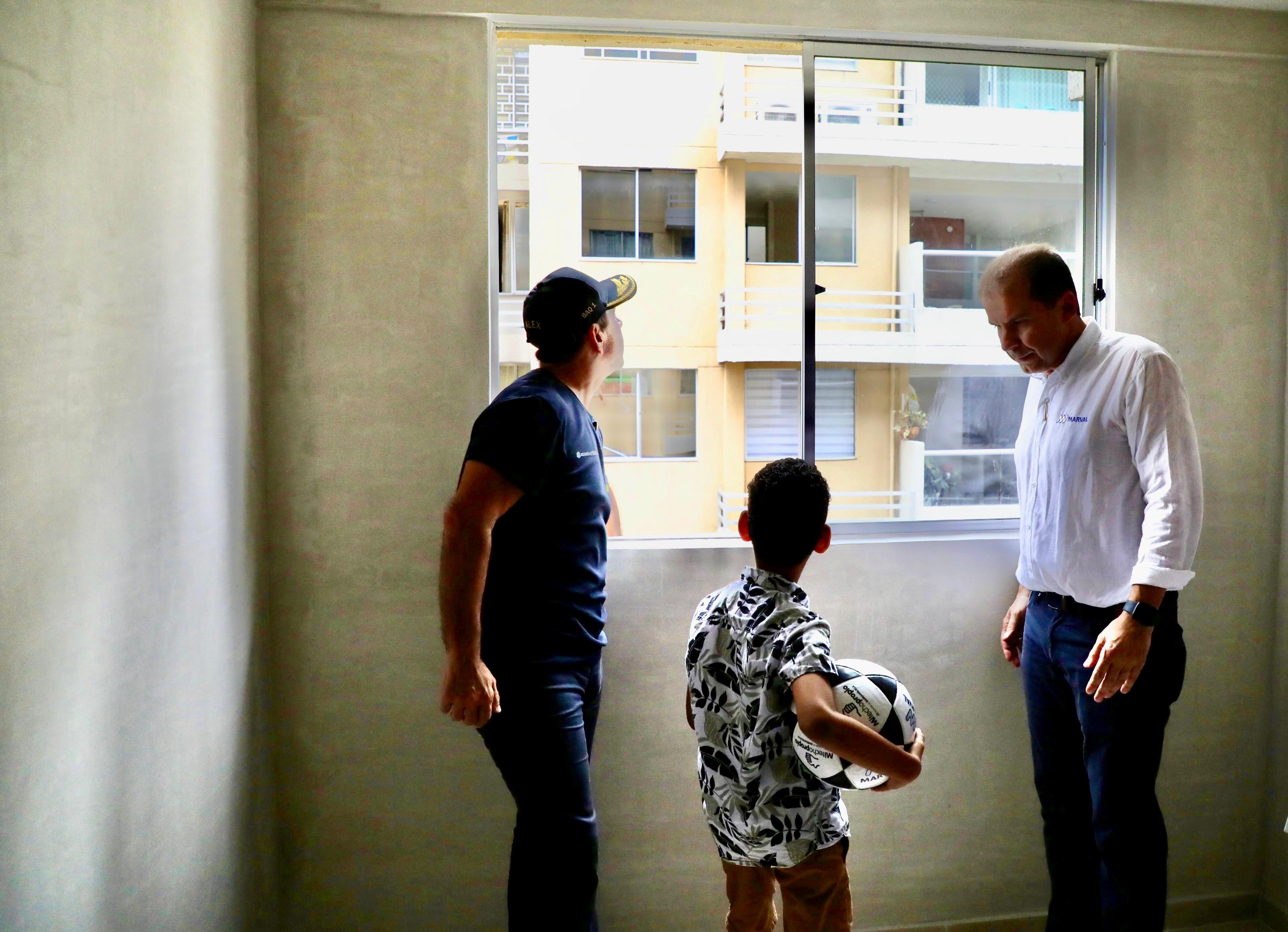 El hijo de Yaris Madarriaga se asoma por una de las ventanas de su nuevo hogar. A su lado, el alcalde y el gerente de Marval