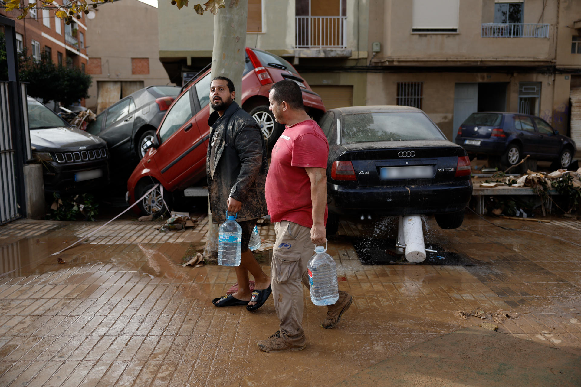 Varios residentes transportan agua potable tras las intensas lluvias de la fuerte Dana.