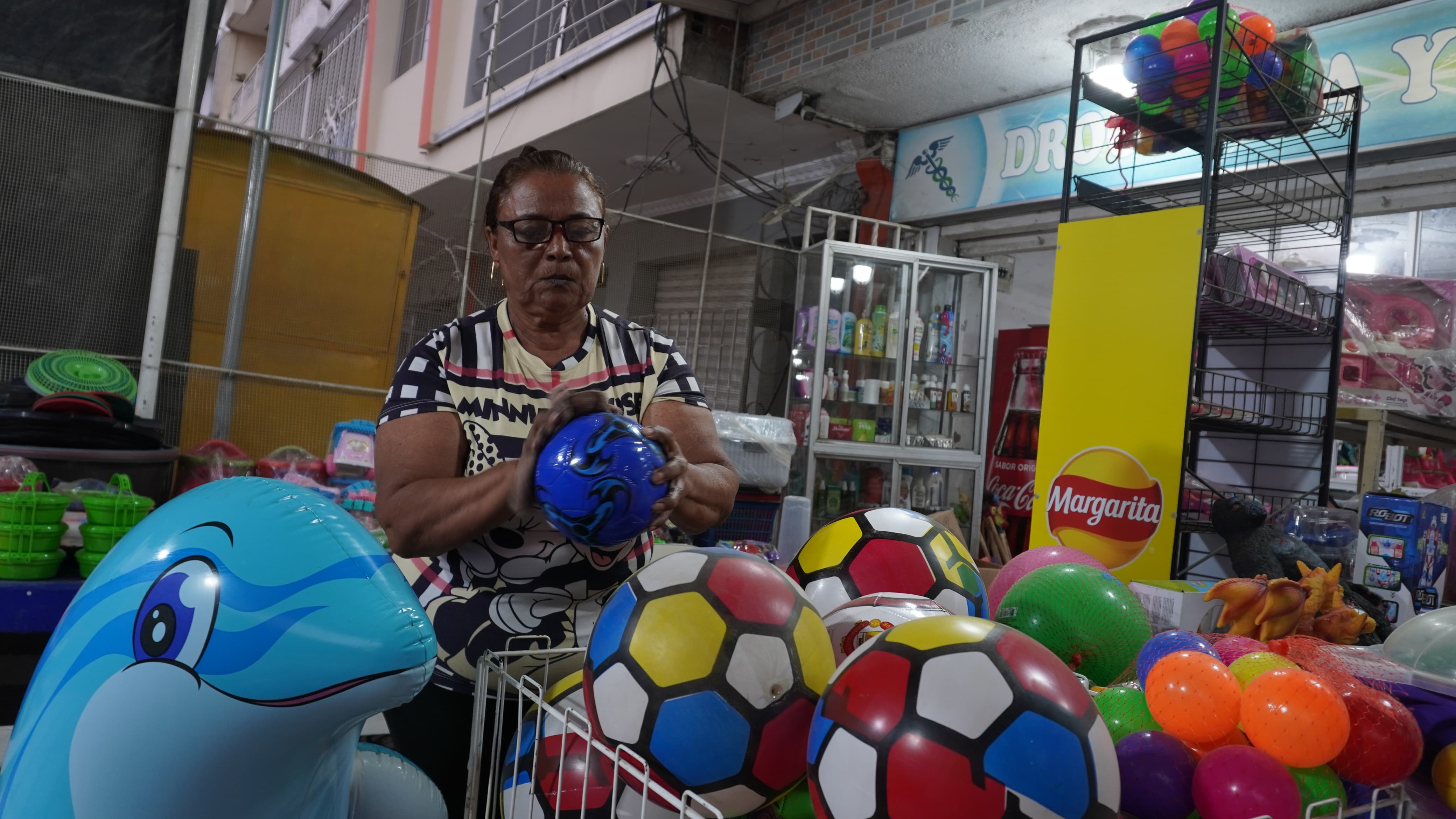 Cecilia Pacheco limpia el polvo de los juguetes que vende en su local.