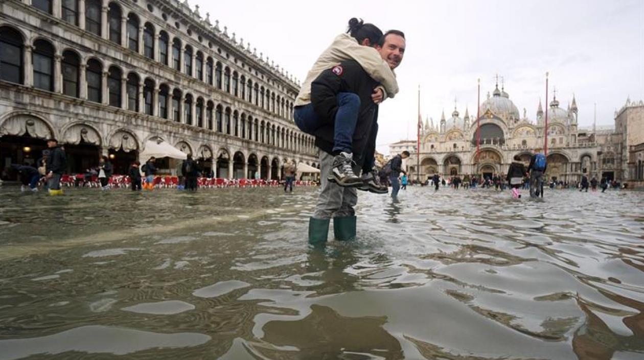 Un hombre carga a sus espaldas con su hija en la Plaza de San Marco, inundada como consecuencia del temporal de lluvia registrado en Venecia, Italia,