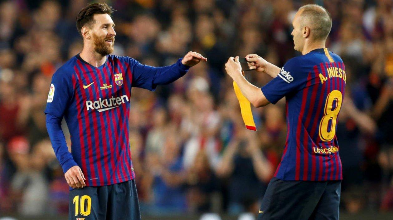 Andrés Iniesta pasa la cinta de capitán a Lionel Messi. 