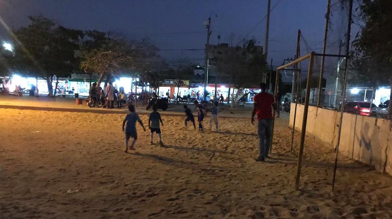 Los niños practicando fútbol bajo precarias condiciones de iluminación.
