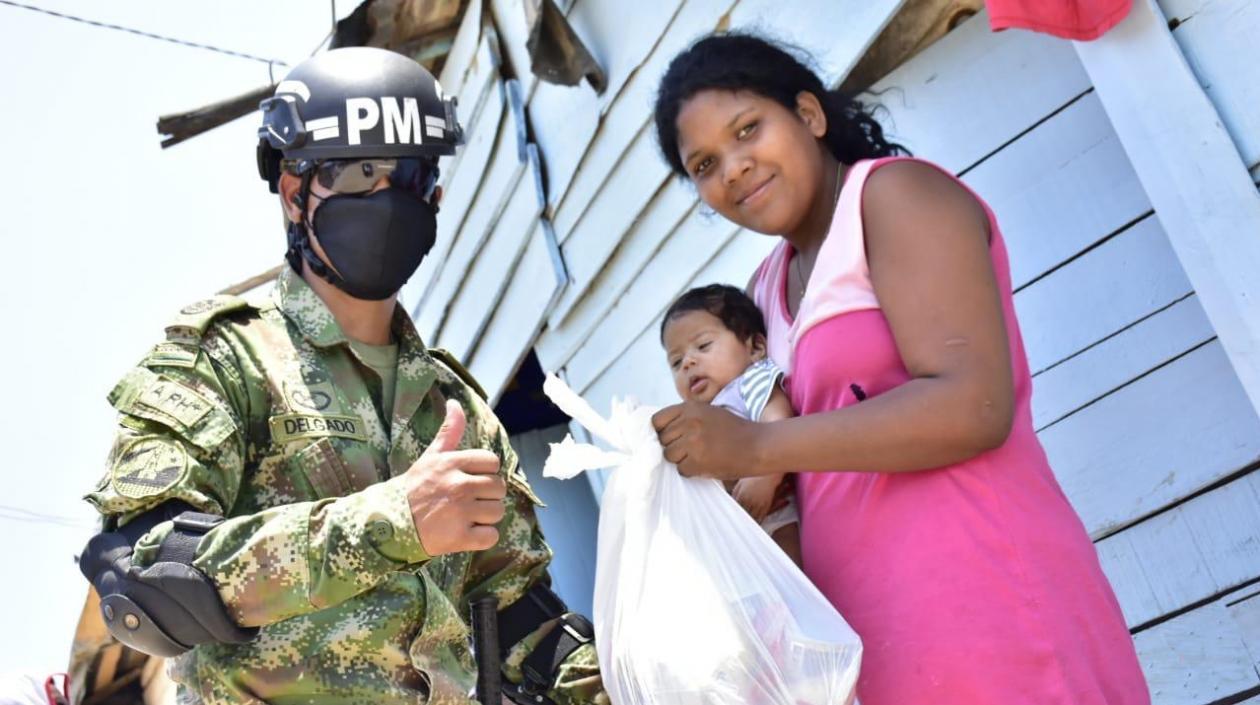 Un miembro de la Policía Militar apoya la labor de entrega de mercados en los barrios Las Flores, Siape y La Playa.