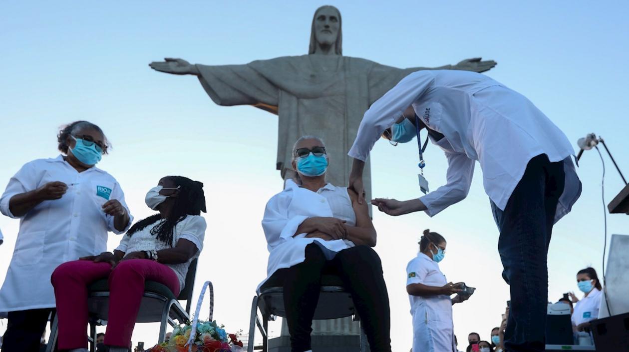 Dos mujeres son vacunadas hoy, lunes en un acto simbólico a los pies de la emblemática estatua del Cristo Redentor en el cerro del Corcovado, en Río de Janeiro. 