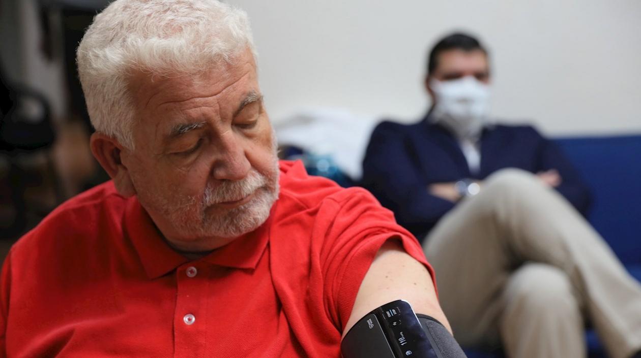 Un hombre espera mientras le toman la presión arterial. 