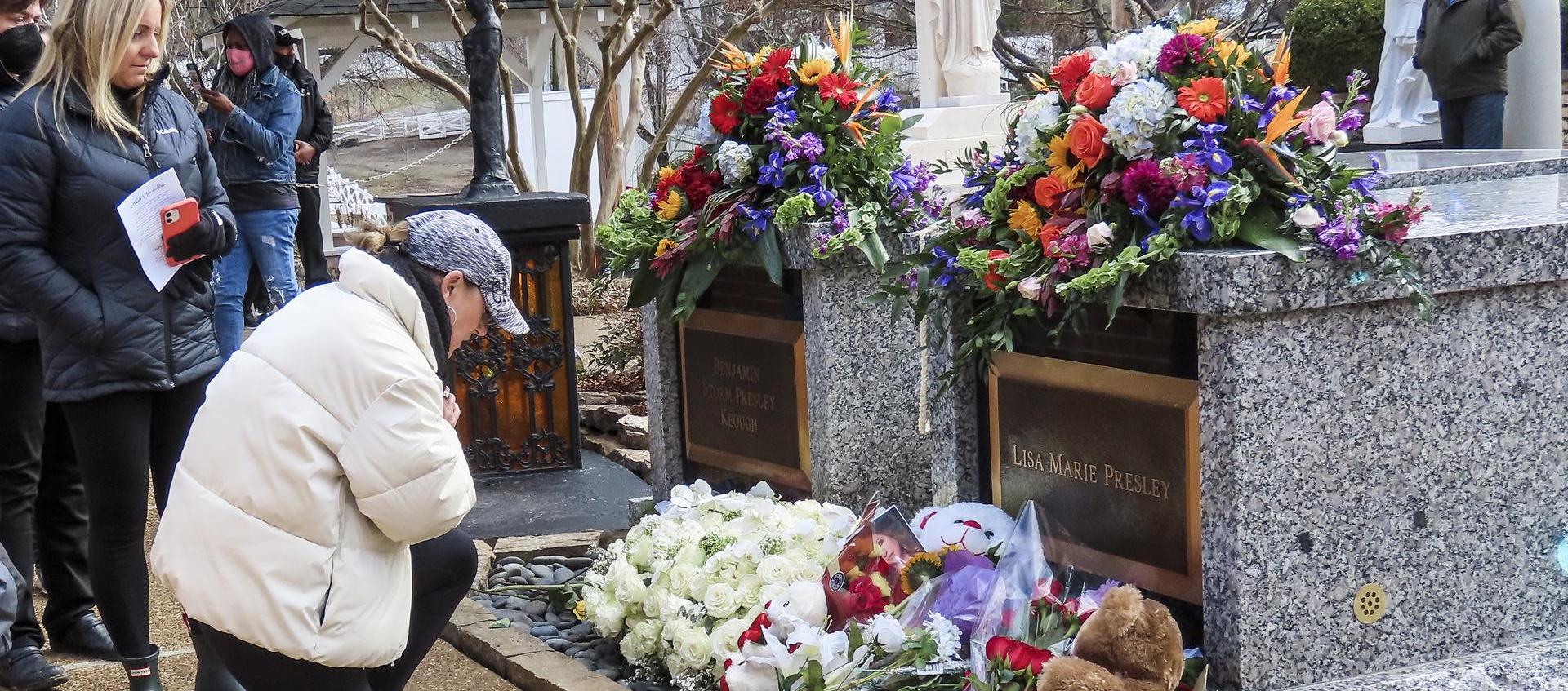 Una mujer se arrodilla ante la tumba de Lisa Marie Presley en Graceland, el hogar del cantante y actor estadounidense Elvis Presley.