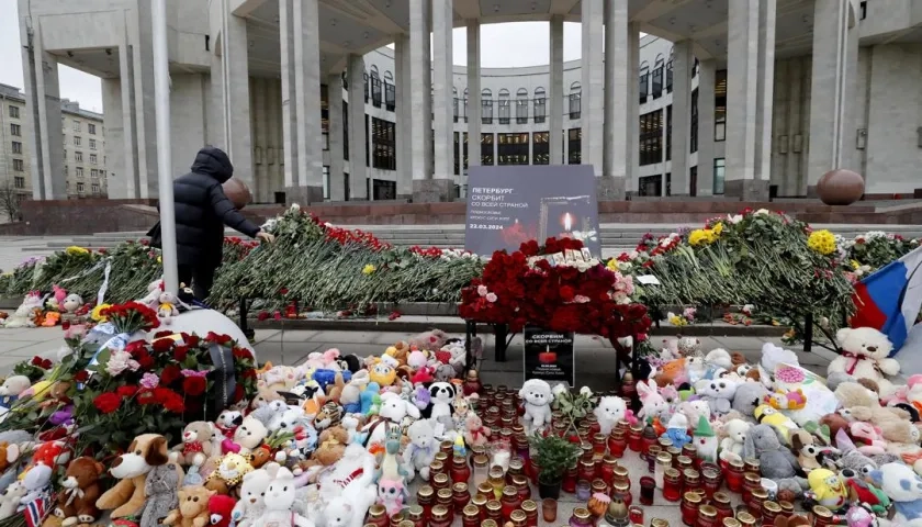 Una mujer deposita flores en un monumento improvisado frente a la Biblioteca Nacional Rusa.