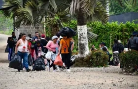 Migrantes cargando sus pertenencias en la entrada a la selva del Darién.