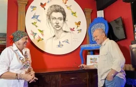 Carla Celia y Joaquín Botero frente a una pintura y una silla restaurada que hacen parte de la exposición de arte de Nonna Rosa