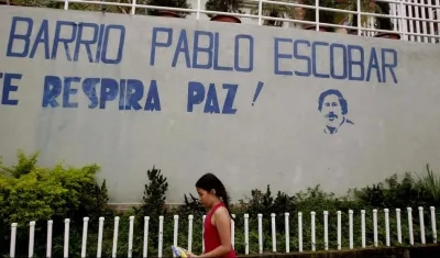 Una niña camina frente al mural que da la bienvenida al barrio Pablo Escobar en Medellín