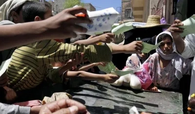 Niños entregan sus cartillas para recibir una ración de comida en un punto de distribución en Saná (Yemen). 