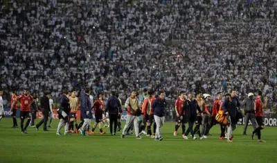 Jugadores de Independiente abandonan la cancha tras los disturbios en las tribunas.
