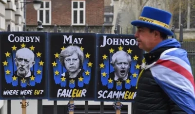 Un manifestante a favor de la estancia del Reino Unido en la Unión Europea camina, este martes, junto a carteles que critican a Jeremy Corbyn (i), Theresa May y Boris Johnson en Londres (Reino Unido). 