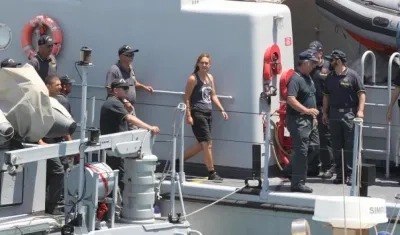 Carola Rackete (c), capitana del buque de rescate Sea Watch 3, es escoltada por efectivos de la Guardia di Finanza italiana a su llegada a Porto Empedocle (Italia) este lunes. 