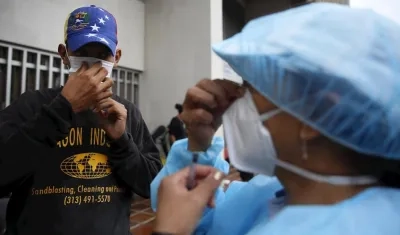 Un hombre venezolano recibe un tapabocas este lunes en la Alcaldía de Cali.