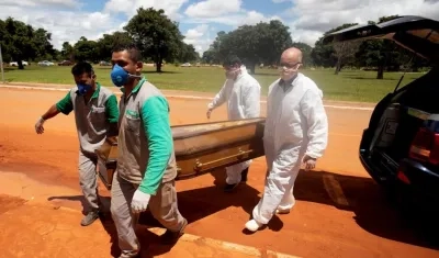 Trabajadores cargan un féretro con una víctima mortal de Covid-19 rumbo a su entierro en el cementerio Campo da Esperança, en Brasilia (Brasil). 