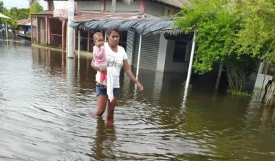 Una mujer y su hijo caminan entre las aguas desbordadas en Sucre.