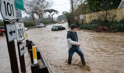 Un ciudadano camina entre una vía totalmente inundada en California.