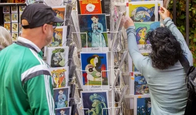  Turistas miran postales del artista español Pablo Ruiz Picasso.
