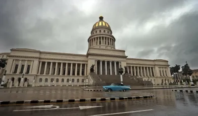 Una persona conduce hoy un vehículo bajo la lluvia, frente al Capitolio en La Habana. 