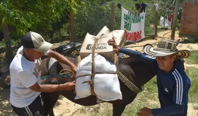 Dos personas transportando cajas con ayuda alimentaria que hacen parte de los kits entregados a los habitantes de la vereda Rancho Quemado, a cuatro horas de Segovia 