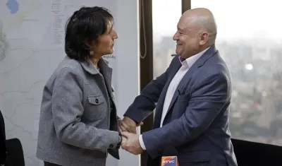 La directora del Centro Nacional de Memoria Histórica, María Gaitán (i), estrecha la mano del senador Julián Gallo, quien fue exjefe guerrillero bajo el nombre 'Carlos Antonio Lozada'. 