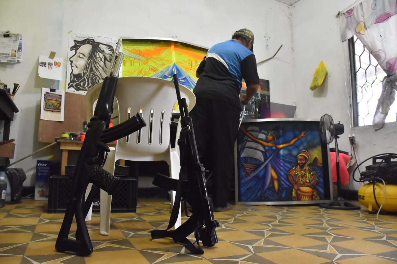 Armando Ibañez en plena acción. Pintando un picó en la sala de su casa, teniendo como primer plano sus dos "fusiles". 