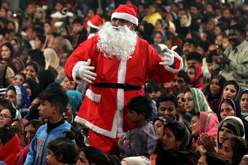 Un hombre disfrazado de Santa Claus junto a varios cristianos paquistaníes que sisten a una misa en Lahore (Pakistán).