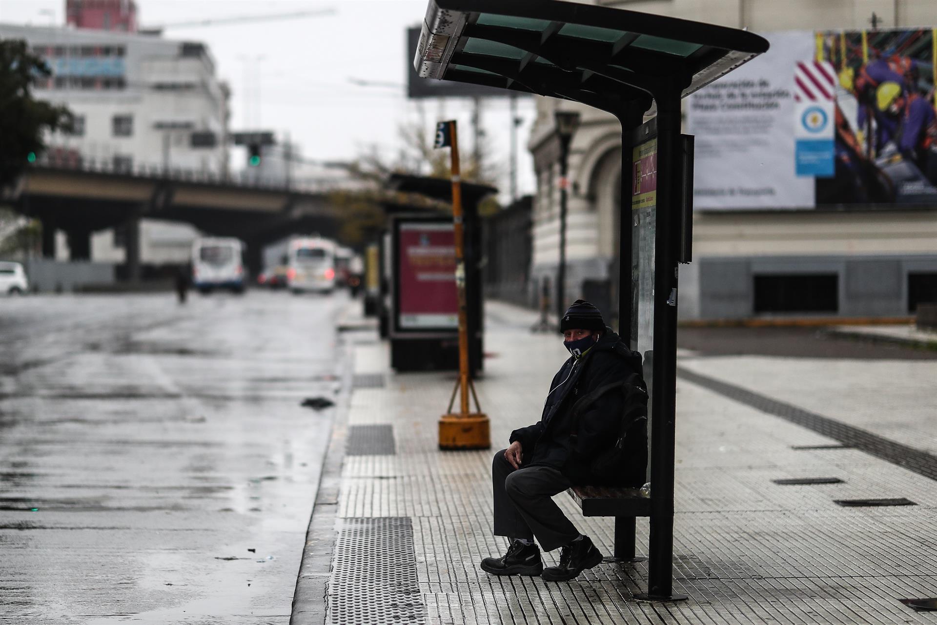 Una persona se sienta en una parada de autobús que se encuentra solo hoy, en Buenos Aires.