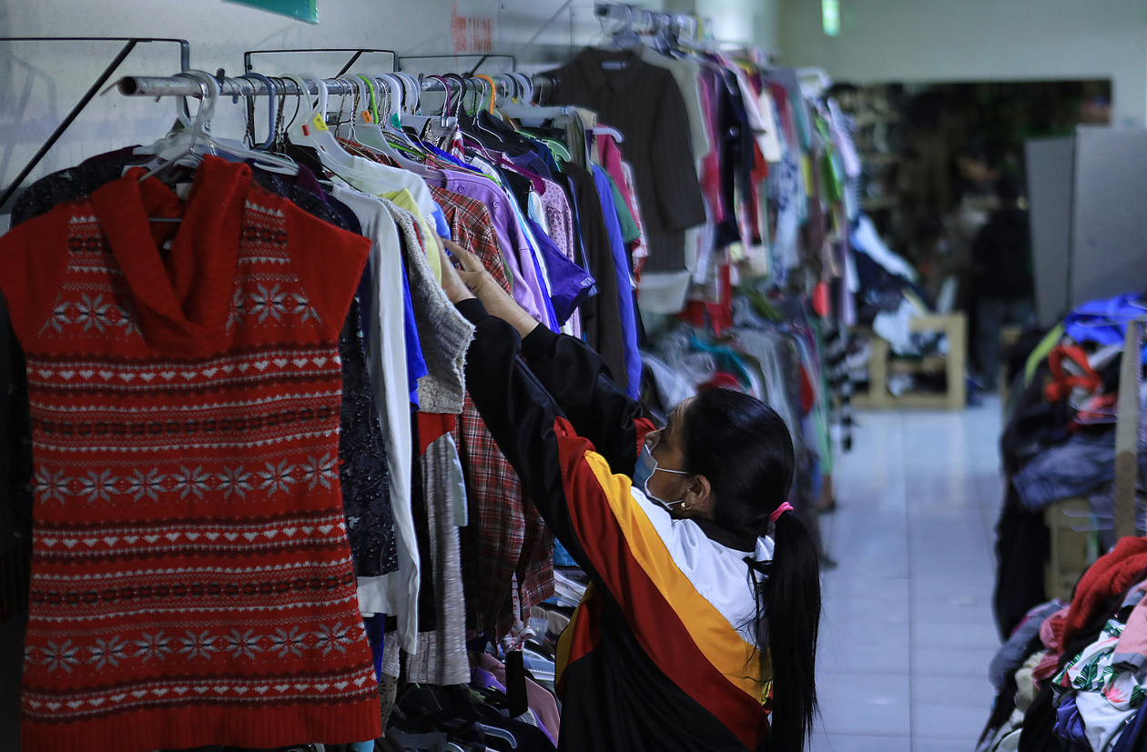 Una mujer migrante venezolana selecciona ropa donada por activistas para afrontar el frio en 'Gratis Tienda'.