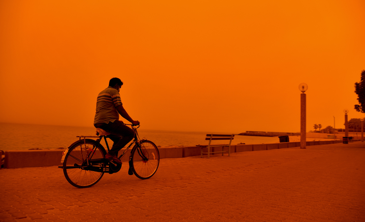  Un hombre monta en bicicleta durante una fuerte tormenta de polvo en la ciudad de Kuwait.