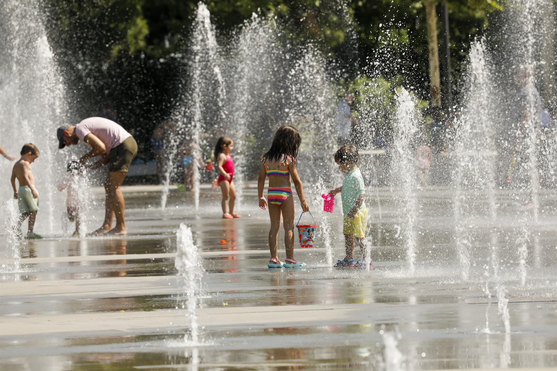 Niños y adutos se refrescan en una fuente en España para paliar temperaturas de hasta 41 grados.