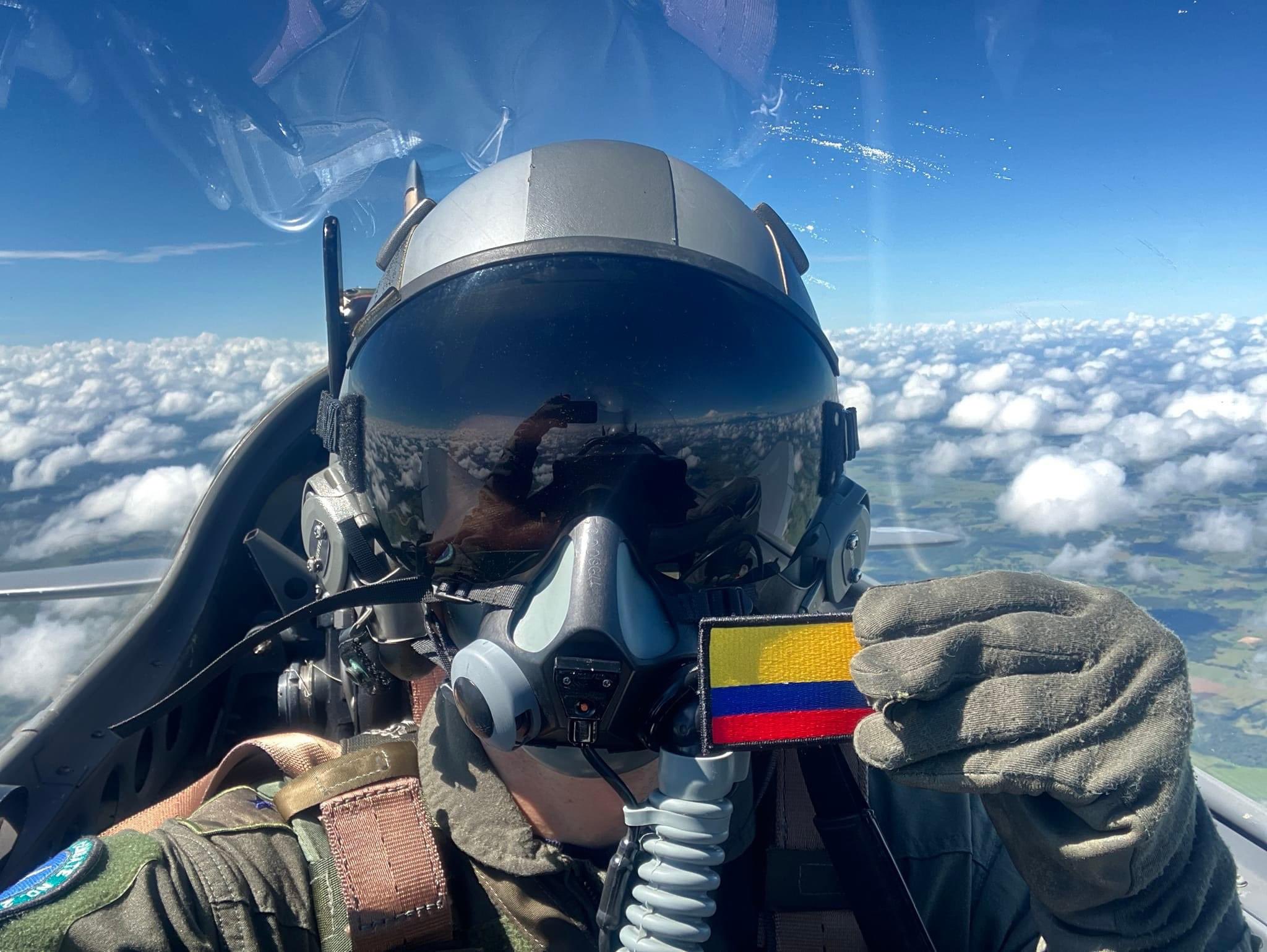 Desde lo alto, un piloto de la Fuerza Aérea muestra una bandera de Colombia.