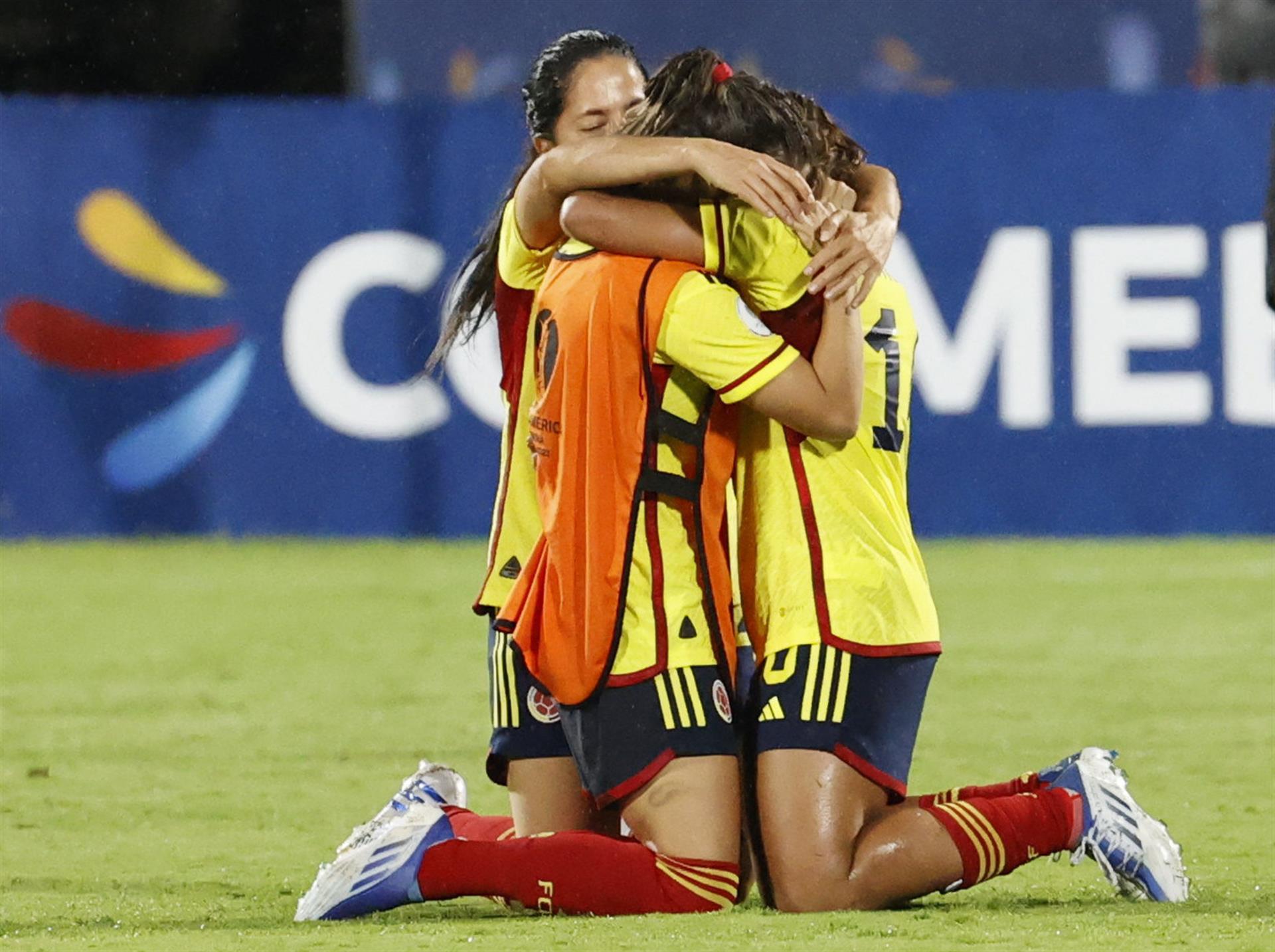 Tres jugadoras de Colombia se arrodillan para celebrar.