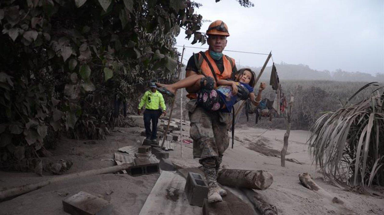 Un trabajador de los equipos de rescate de Guatemala ayuda a una niña en El Rodeo, Escuintla (Guatemala).