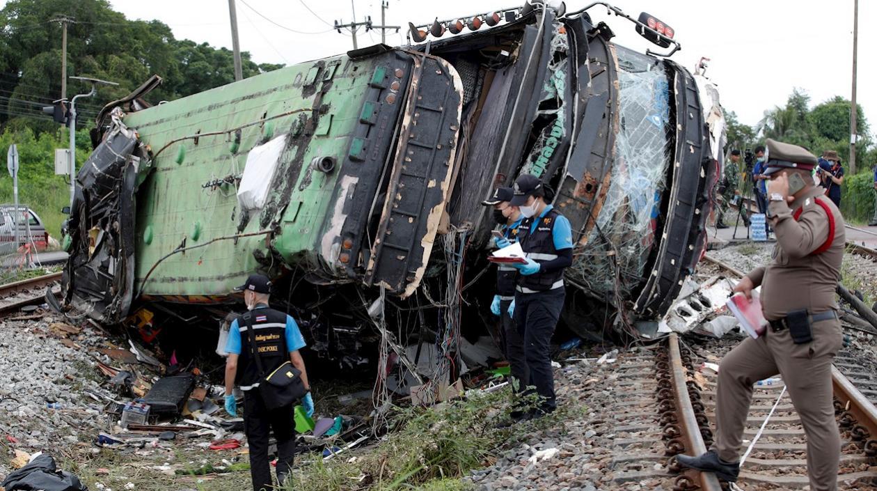 La policía tailandesa trata de reunir evidencias en el lugar donde un bus fue arrollado por un tren.