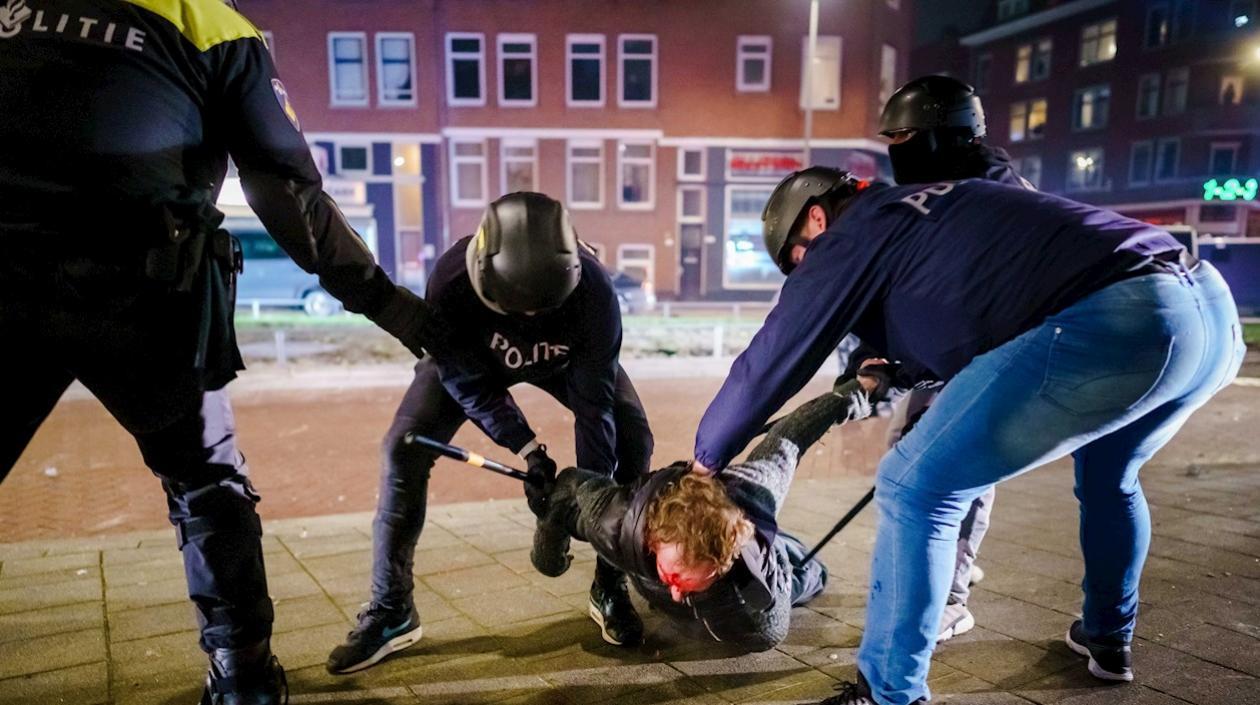 Un hombre es reducido por varios policías durante los disturbios registrados anoche en Rotterdam, Países Bajos. 