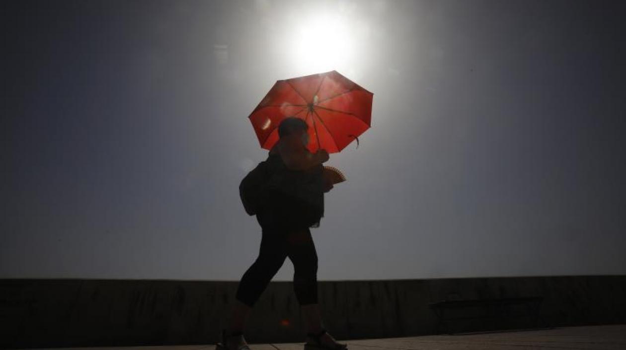 Una mujer camina resguardándose del sol con una sombrilla, en Córdoba, ayer. 