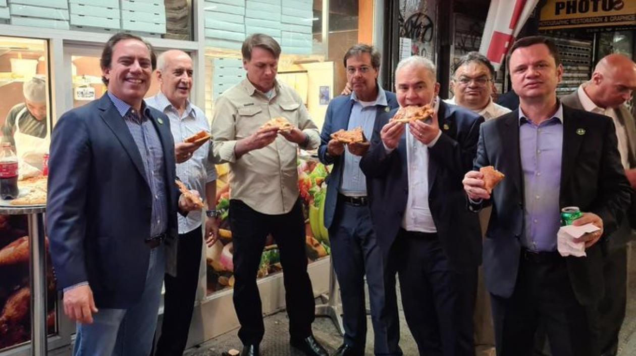 Jair Bolsonaro y miembros de su delegación comiendo pizza en una calle de NY.