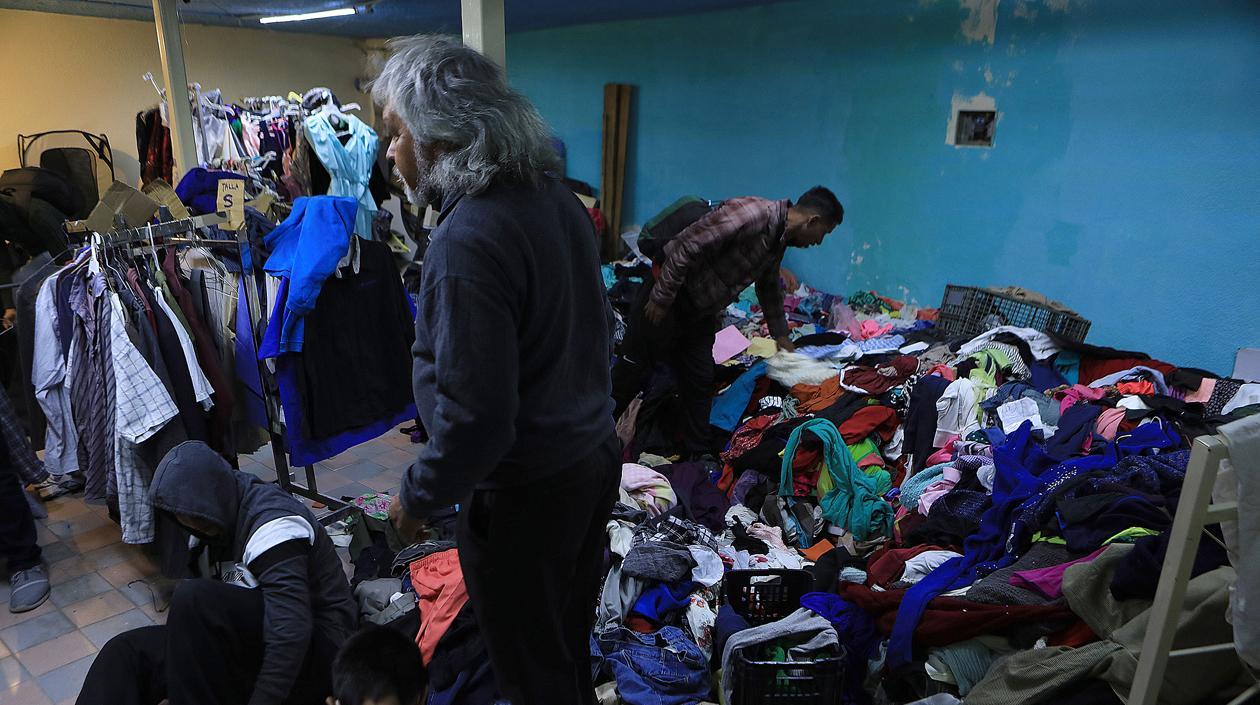 Un grupo de migrantes venezolanos selecciona ropa donada.
