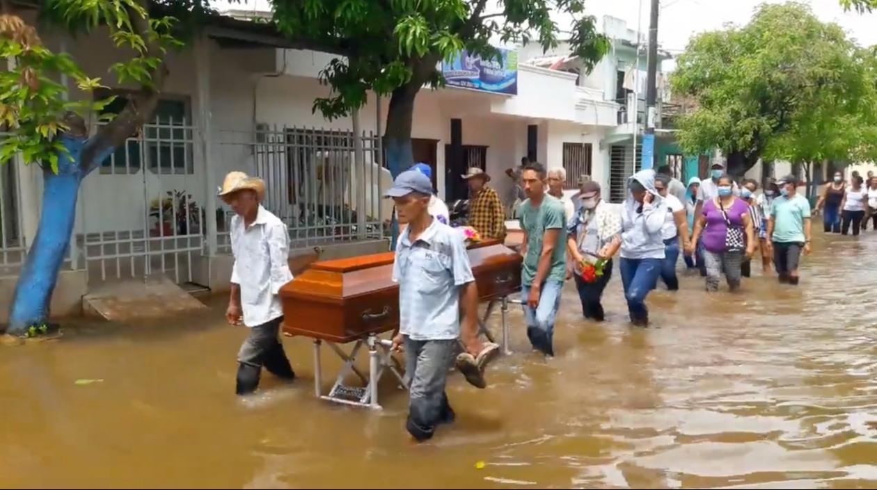 Con los zapatos en sus manos, familiares de la anciana de 90 años cargan su ataúd en La Mojana.