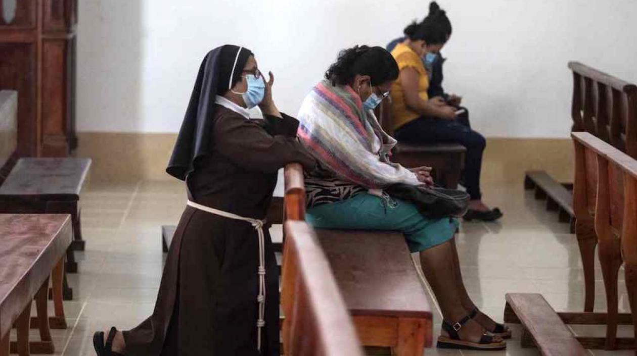 Una monja y dos feligreses orando por la suerte de los jerarcas detenidos.